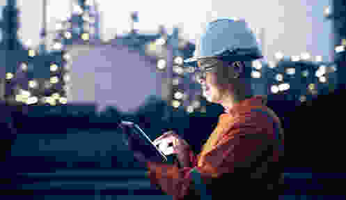 Engineer in front of a refinery checking data on his tablet